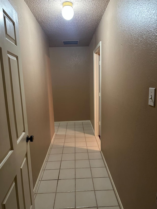 hall with light tile patterned floors and a textured ceiling