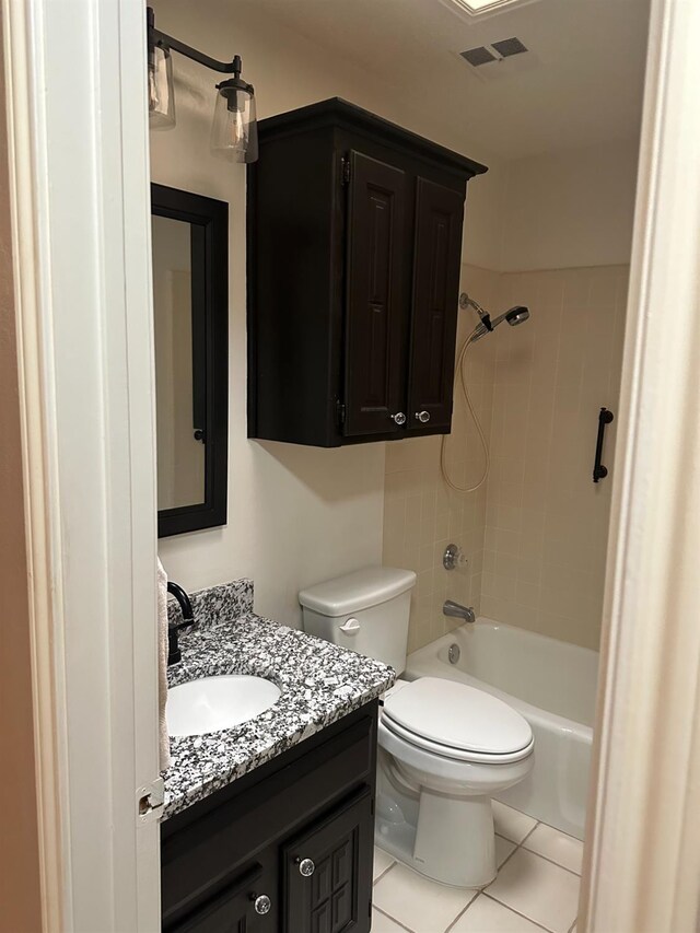 full bathroom featuring tile patterned flooring, vanity, tiled shower / bath, and toilet