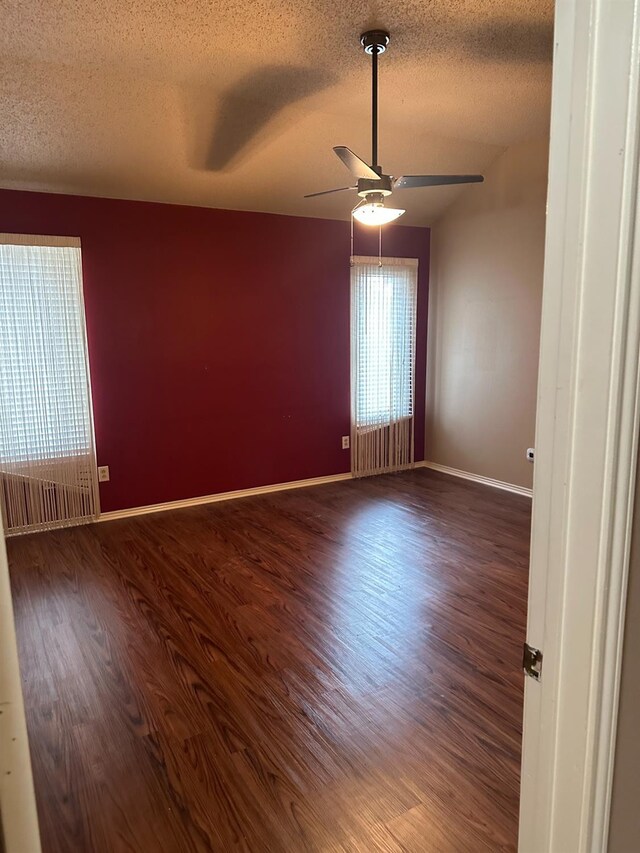 empty room featuring dark wood-type flooring, ceiling fan, and a textured ceiling