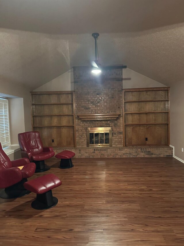 living room with lofted ceiling, a brick fireplace, hardwood / wood-style floors, and a textured ceiling