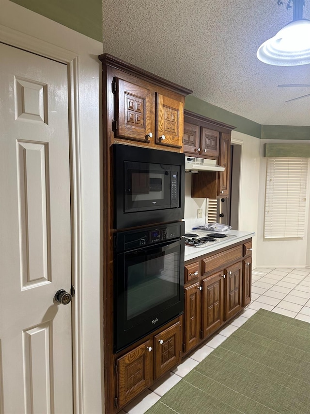 kitchen with light tile patterned floors, dark brown cabinets, black appliances, and a textured ceiling