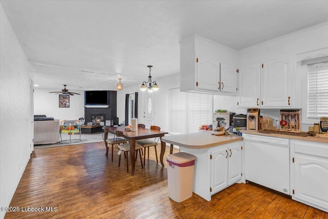 110 E 18th St, Littlefield, TX 79339 - kitchen with white dishwasher, a peninsula, a warm lit fireplace, open floor plan, and white cabinetry