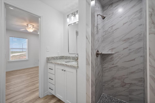 bathroom with ceiling fan, vanity, hardwood / wood-style floors, and a tile shower