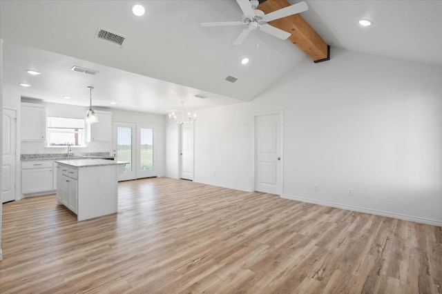 unfurnished living room featuring ceiling fan with notable chandelier, sink, lofted ceiling with beams, and light wood-type flooring