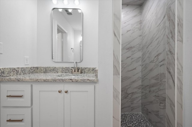 bathroom featuring tiled shower and vanity