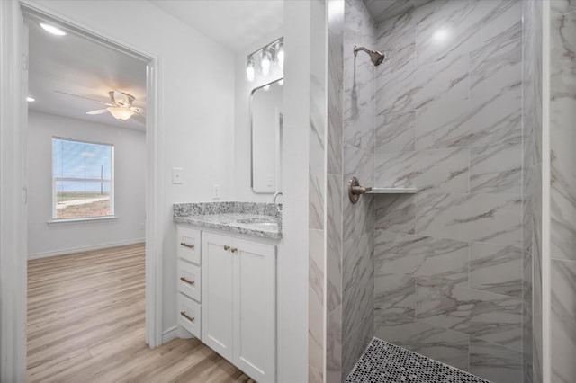 bathroom featuring ceiling fan, vanity, wood-type flooring, and a tile shower