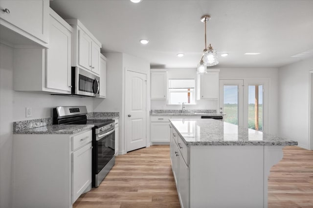 kitchen with a kitchen island, appliances with stainless steel finishes, hanging light fixtures, and white cabinets