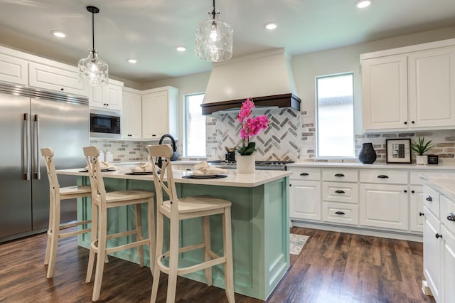 kitchen featuring premium range hood, built in appliances, a center island, and white cabinets