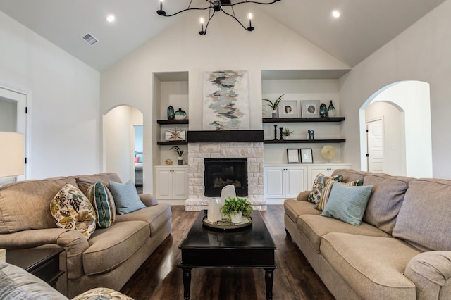 living room with built in shelves, a stone fireplace, a chandelier, high vaulted ceiling, and dark hardwood / wood-style floors