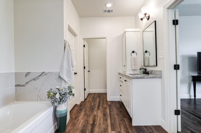 bathroom featuring a tub to relax in, vanity, and wood-type flooring