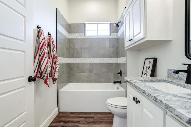 full bathroom with hardwood / wood-style flooring, tiled shower / bath, vanity, and toilet