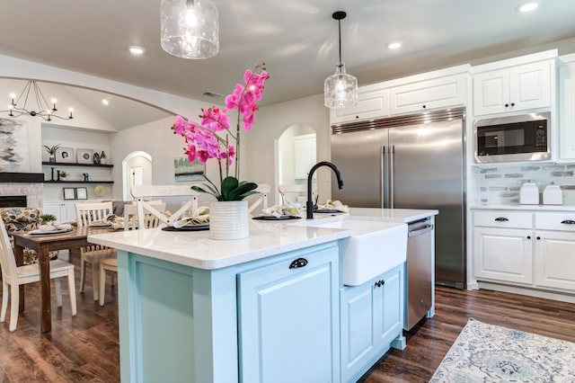 kitchen featuring built in microwave, dishwasher, an island with sink, and white cabinets