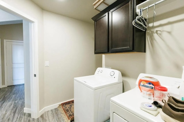 washroom with separate washer and dryer, light hardwood / wood-style flooring, and cabinets