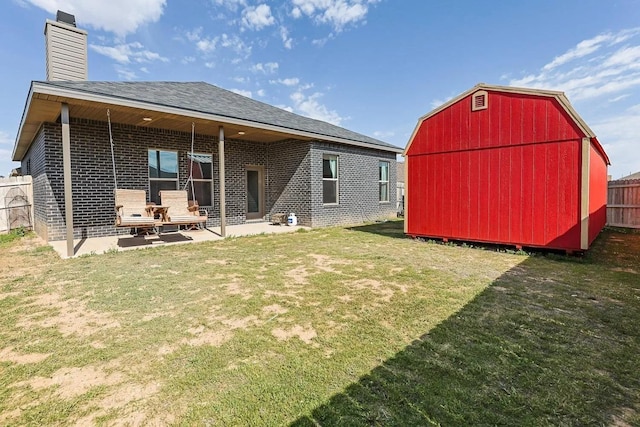 rear view of property with a shed, a lawn, and a patio area