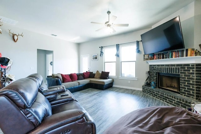 living room with a brick fireplace, wood-type flooring, and ceiling fan