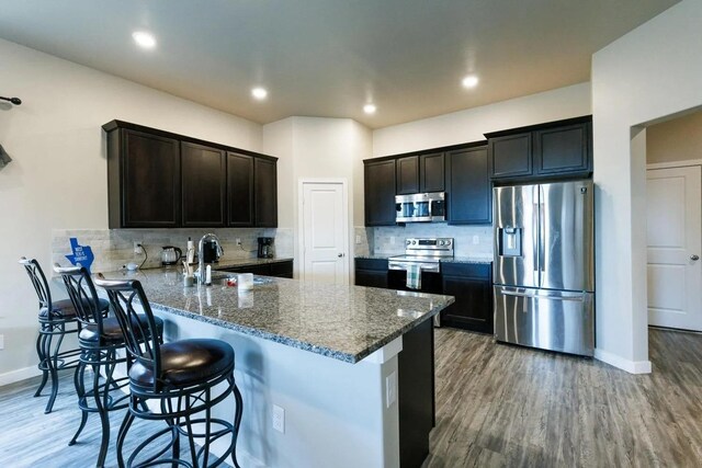 kitchen with stainless steel appliances, a kitchen bar, kitchen peninsula, and backsplash