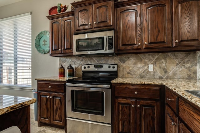 kitchen featuring stainless steel appliances, light stone counters, dark brown cabinetry, and decorative backsplash