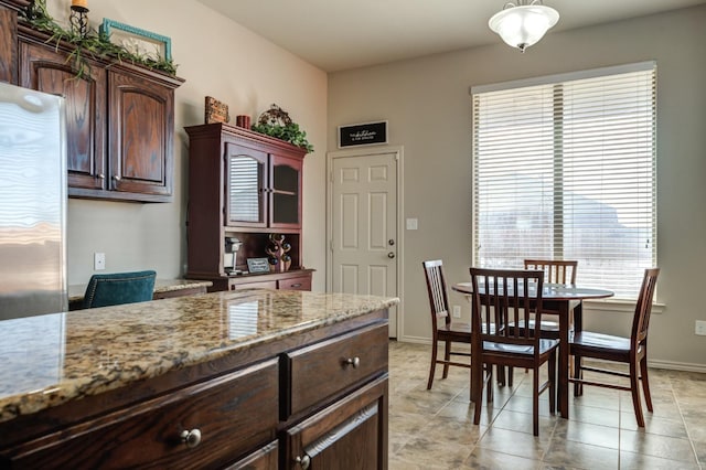 kitchen featuring light tile patterned floors, dark brown cabinets, and light stone countertops