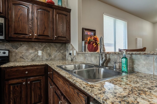 kitchen featuring dark brown cabinetry, sink, stainless steel electric range, and light stone counters