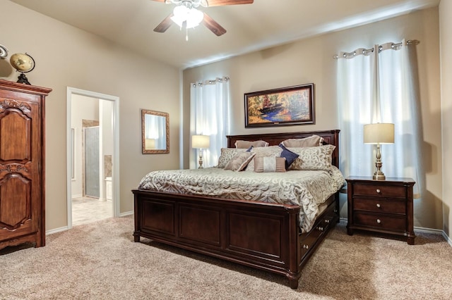 carpeted bedroom featuring multiple windows, ceiling fan, and ensuite bath