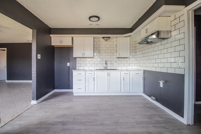 kitchen with tasteful backsplash, sink, and white cabinets