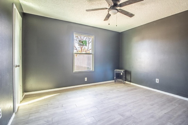 empty room with ceiling fan, a textured ceiling, and light wood-type flooring