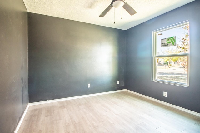 unfurnished room with ceiling fan, a textured ceiling, and light wood-type flooring