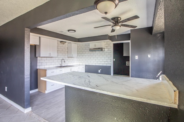 kitchen with tasteful backsplash, sink, white cabinets, and a textured ceiling