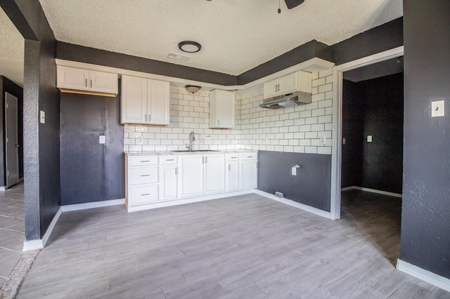 kitchen with sink, decorative backsplash, light hardwood / wood-style floors, and white cabinets