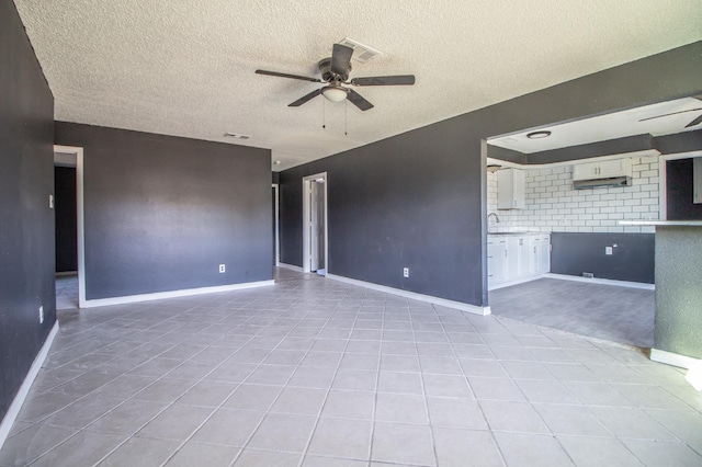 tiled spare room featuring ceiling fan, sink, and a textured ceiling