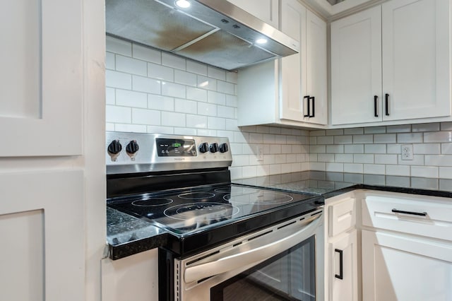 kitchen with stainless steel range with electric stovetop, white cabinetry, decorative backsplash, and dark stone counters