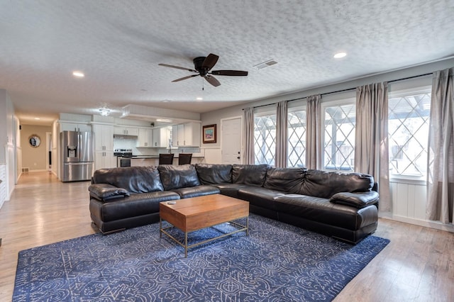 living room featuring ceiling fan, hardwood / wood-style floors, and a textured ceiling