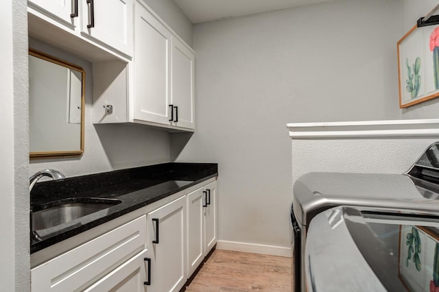 laundry area featuring sink, light hardwood / wood-style flooring, cabinets, and washing machine and clothes dryer