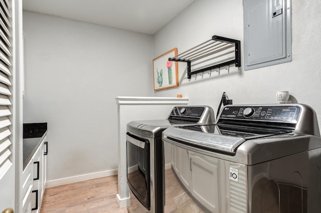 washroom featuring cabinets, separate washer and dryer, electric panel, and light hardwood / wood-style flooring