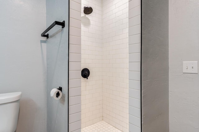 bathroom featuring toilet and a tile shower