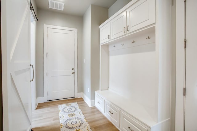 mudroom with a barn door and light hardwood / wood-style flooring