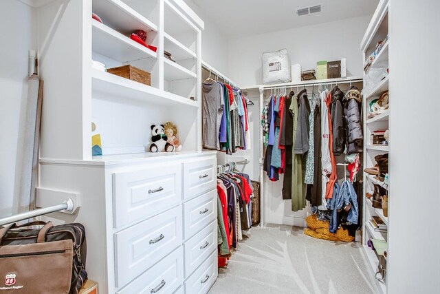 walk in closet with light carpet