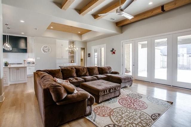 living room featuring beamed ceiling, plenty of natural light, and light hardwood / wood-style flooring