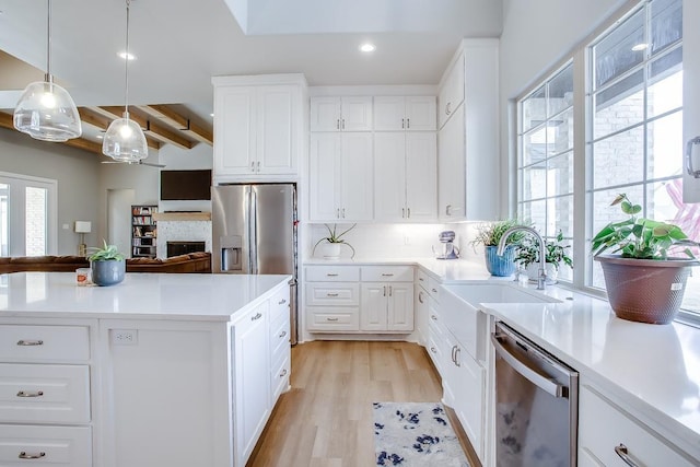 kitchen featuring pendant lighting, sink, backsplash, stainless steel appliances, and white cabinets