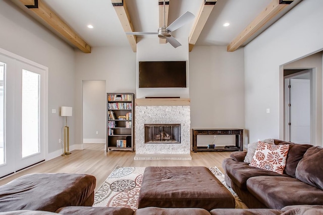 living room featuring ceiling fan, beam ceiling, and light hardwood / wood-style flooring