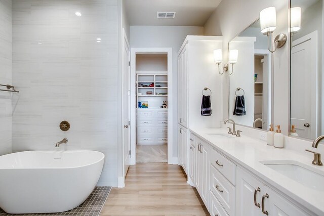 bathroom with a washtub, hardwood / wood-style floors, and vanity