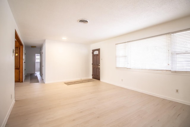 empty room featuring visible vents, baseboards, and light wood-style floors