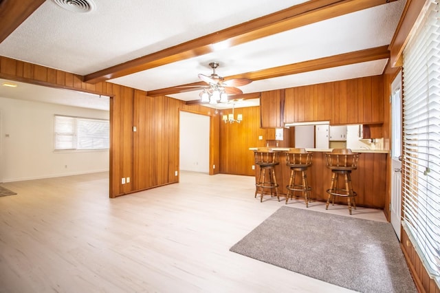 kitchen featuring freestanding refrigerator, brown cabinetry, visible vents, open floor plan, and beam ceiling