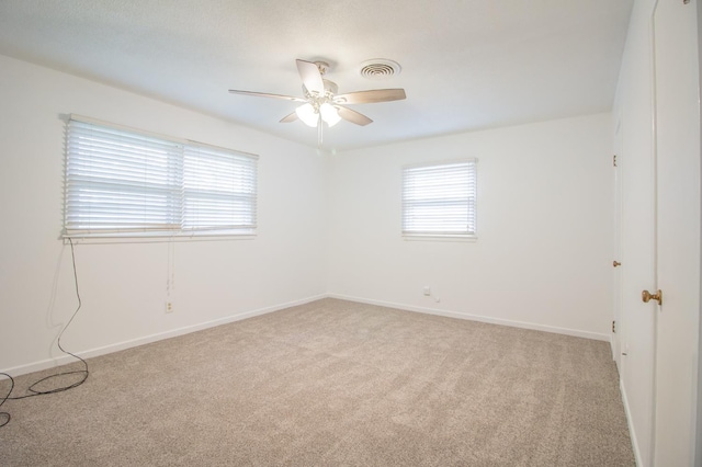 unfurnished room featuring light colored carpet, a ceiling fan, visible vents, and plenty of natural light