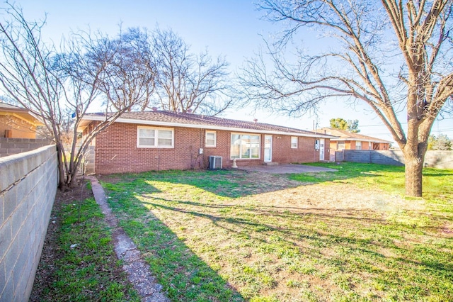 back of property featuring central AC unit, a yard, fence, and brick siding