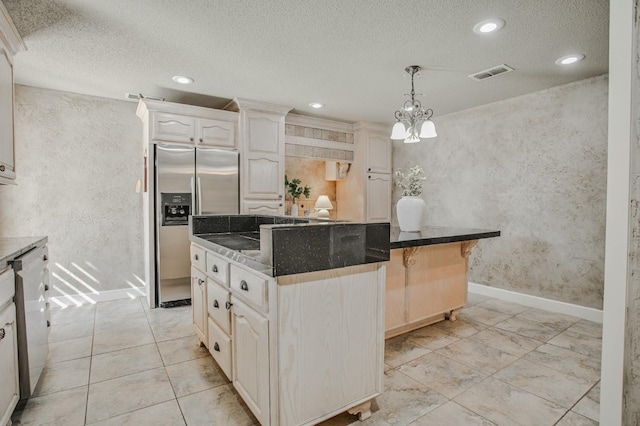 kitchen featuring stainless steel refrigerator with ice dispenser, a kitchen island, pendant lighting, and a textured ceiling