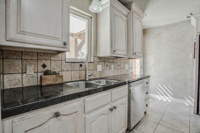 kitchen featuring light tile patterned floors, sink, dishwasher, backsplash, and a textured ceiling