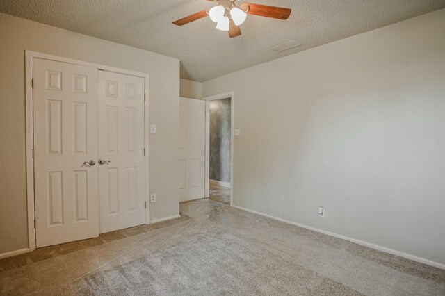 unfurnished bedroom featuring ceiling fan, light colored carpet, a closet, and a textured ceiling