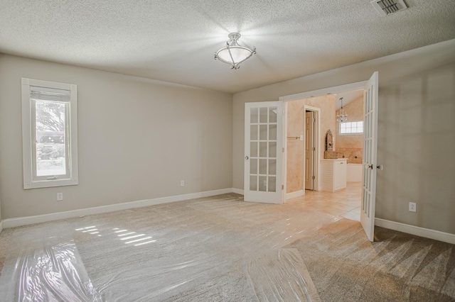 carpeted spare room featuring french doors and a textured ceiling