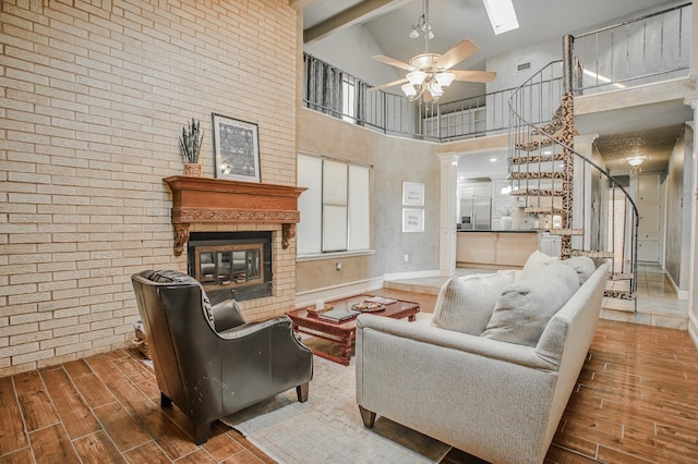 living room featuring ceiling fan, a towering ceiling, and a fireplace